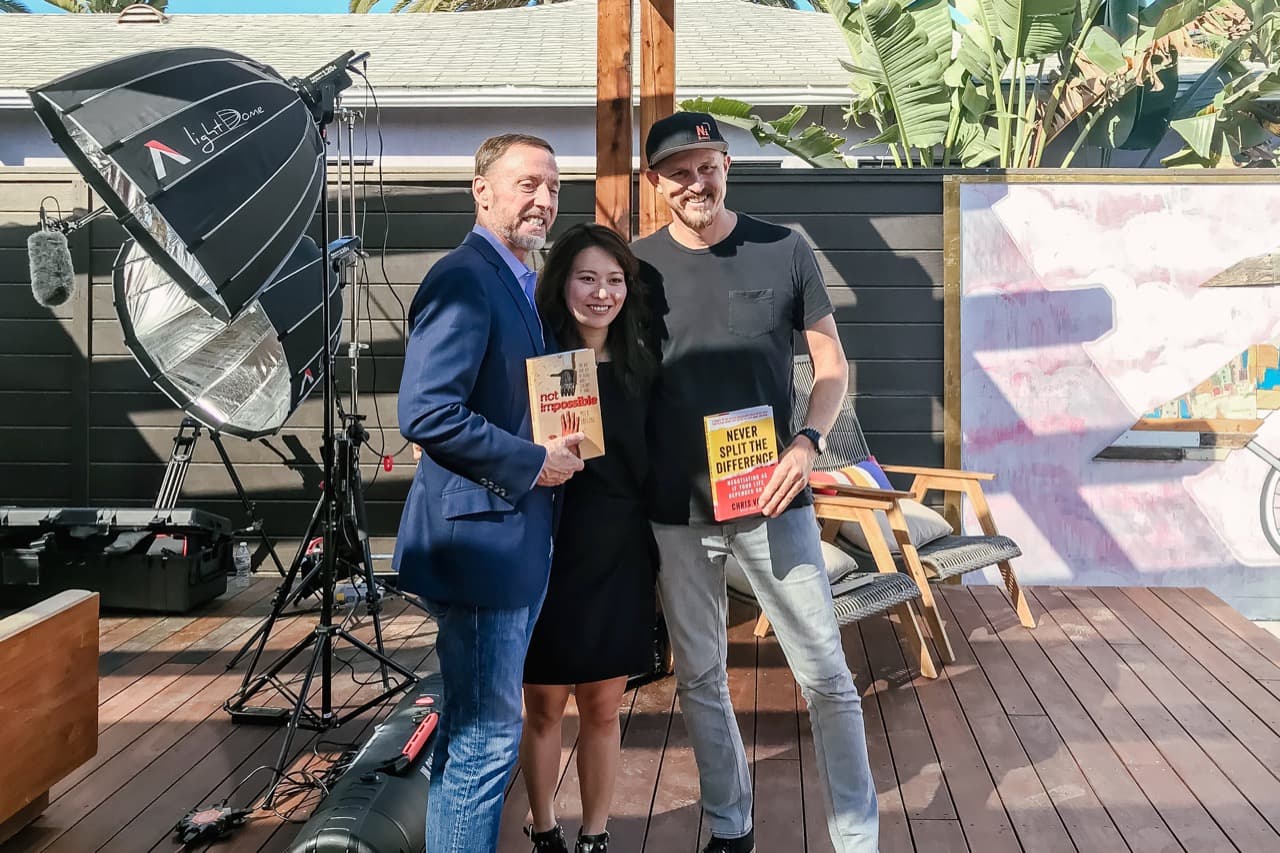 Chris Voss, Fei Wu, and cinematographer holding their books on set