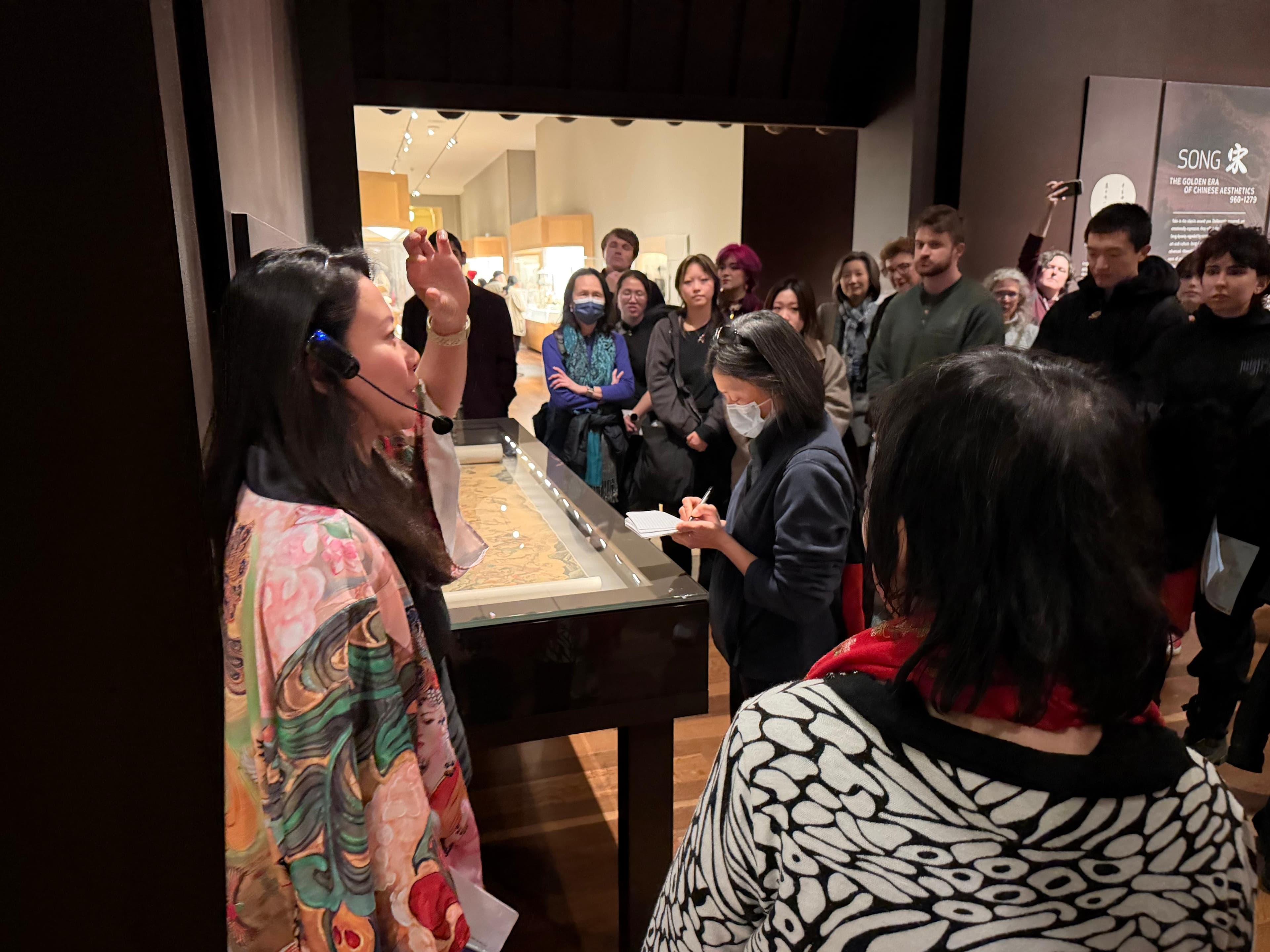 Fei Wu explaining Song Dynasty exhibition to engaged audience