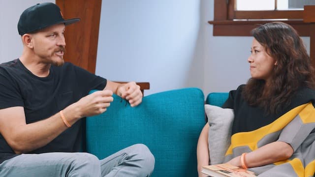 Mick Ebeling and Fei Wu on a teal couch in the Feisworld documentary
